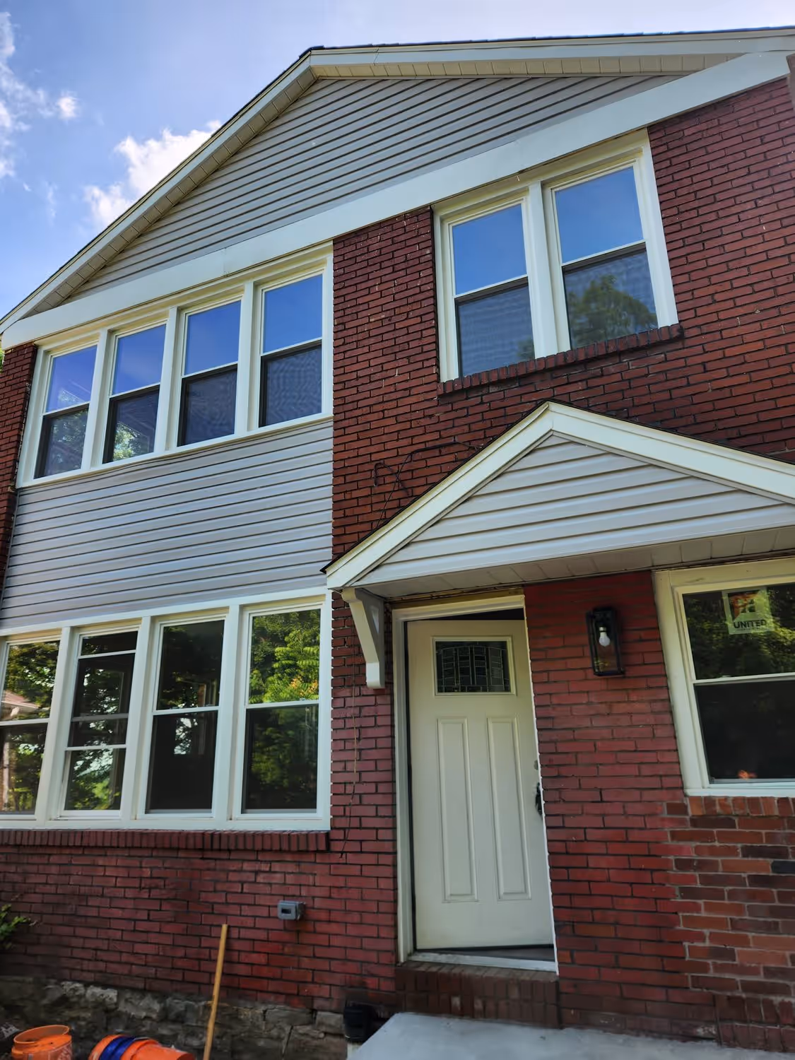 Renovated two-story brick house at 438 N. Fairmount with new cream siding, new windows, and a rebuilt front entry