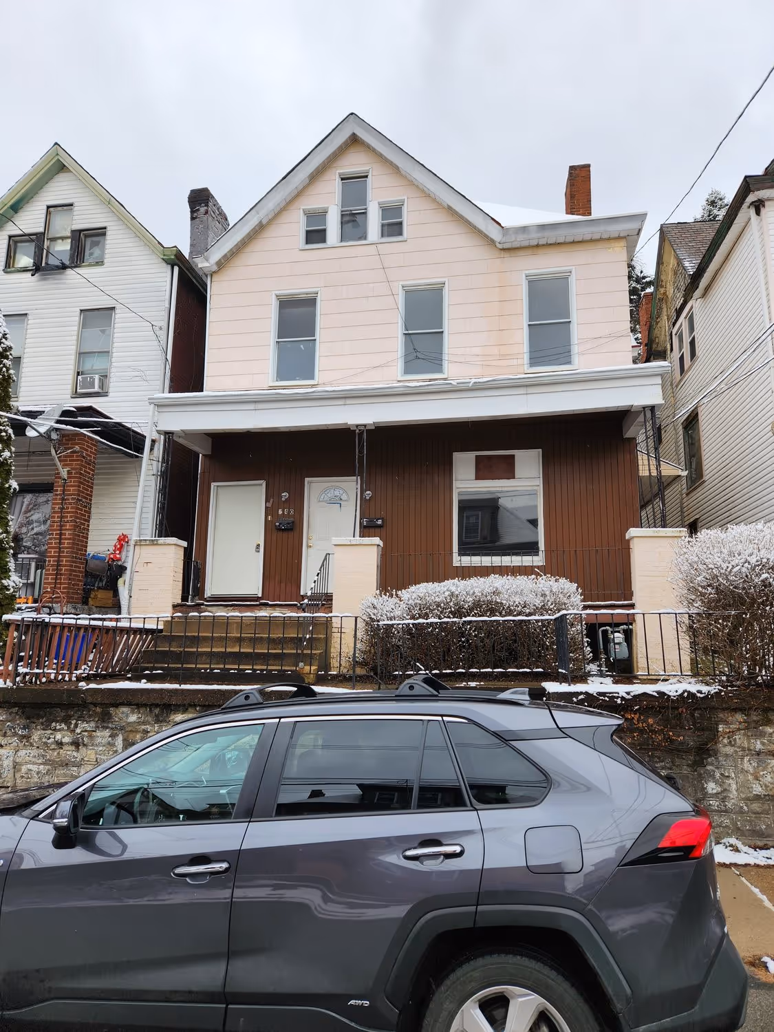240 Kennedy before renovation, brown siding and a worn front porch in the snow