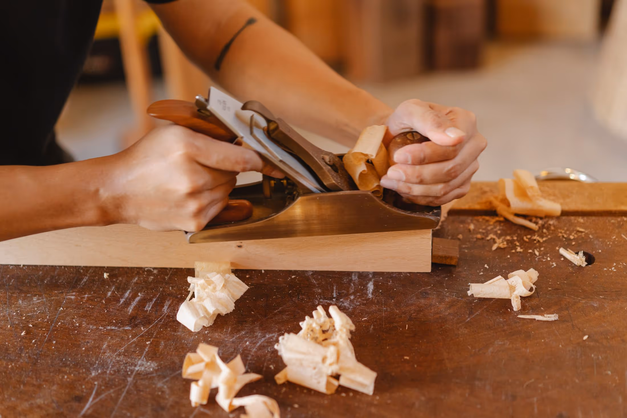Carpenter's hands smoothing a wooden board with a hand plane