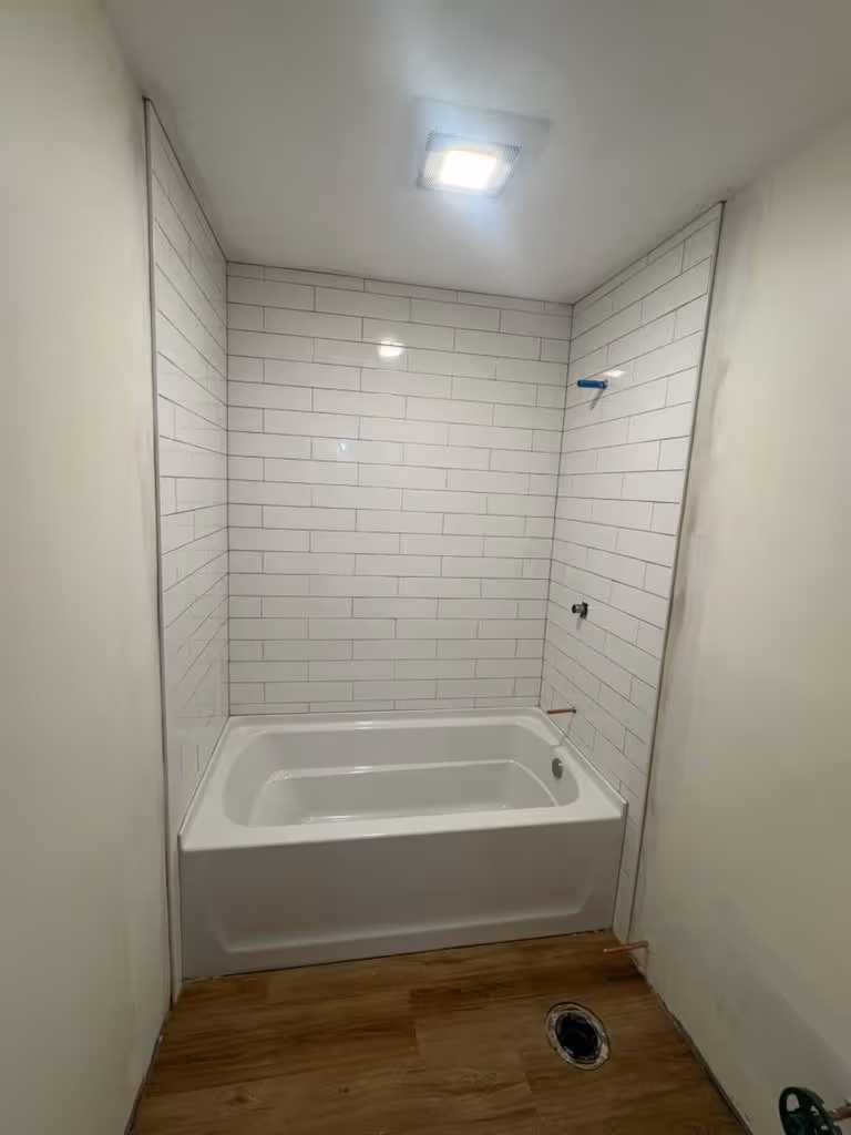 A freshly tiled tub surround at Rankin, subway tile set and grouted, shower hardware not yet installed
