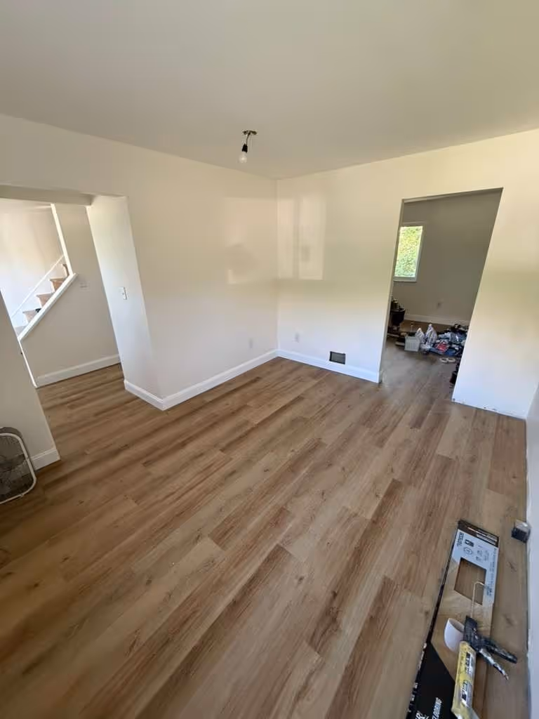 New plank flooring half laid in a repainted room at Rankin, flooring boxes and tools still on the floor